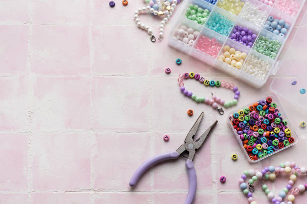 istock Colorful beads and jewelry making tools arranged on pink tile surface 2184513517