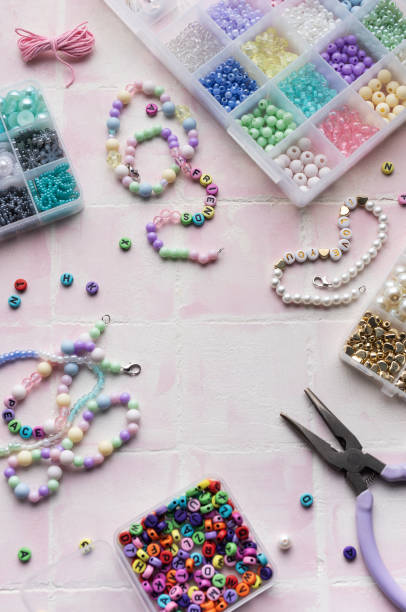 istock Colorful beads and jewelry making tools arranged on pink tile surface 2184513518