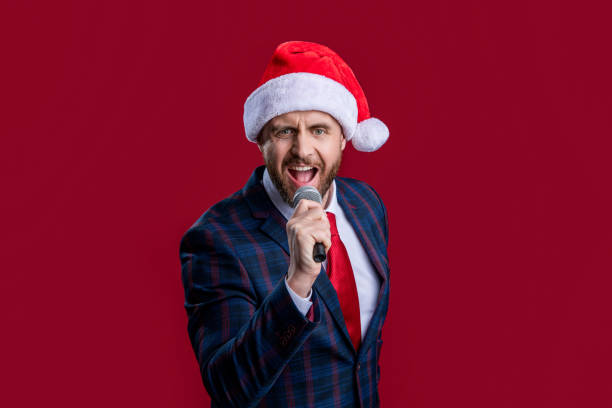 istock happy xmas event host man singing in santa hat. event host man singing with microphone. 2184513906
