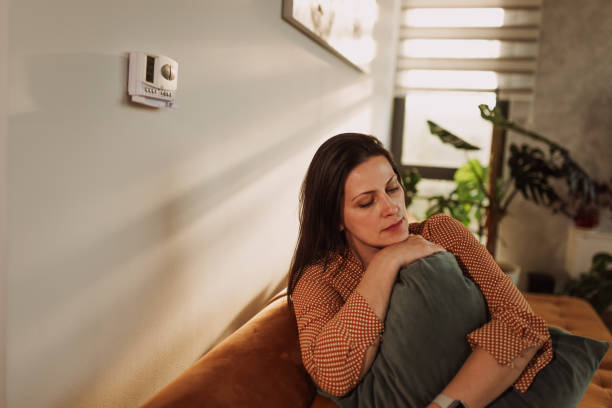 istock Woman Relaxing on Sofa with Cushions in Sunlit Room 2184517834