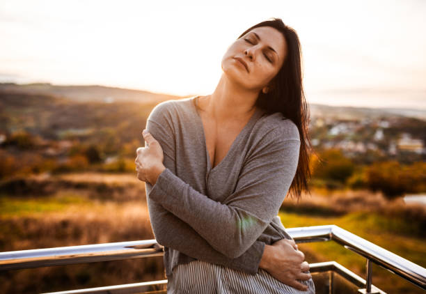 istock Woman Embracing Herself in Tranquil Outdoor Sunset Setting 2184517853