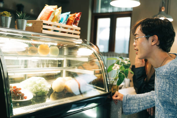 istock Young Man Browsing Fresh Food Options at Cafe Display Case 2184518586