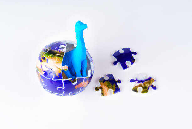 Blue dinosaur emerging from a globe made of puzzle pieces with scattered additional pieces on a white background, symbolizing the idea of prehistoric creatures emerging into the modern world.
