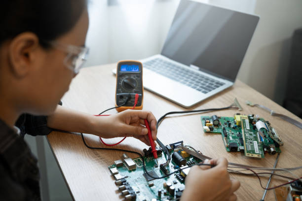 istock A woman is working on a computer part. She is wearing safety glasses and is using a multimeter 2184524395