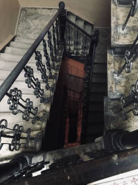 istock Vintage spiral staircase with ornate iron railing in dimly lit building 2184525671