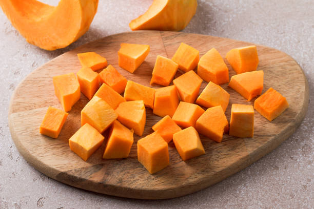 istock Pumpkin cut into pieces on a wooden board on a beige textured background 2184526521