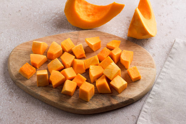 istock Pumpkin cut into pieces on a wooden board on a beige textured background 2184526529