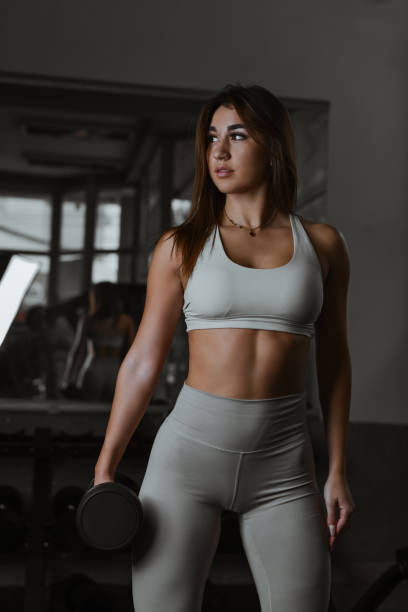 istock Beautiful Fit Woman Wearing Matching Workout Set Holding Dumbbell and Looking Sideway 2184526896