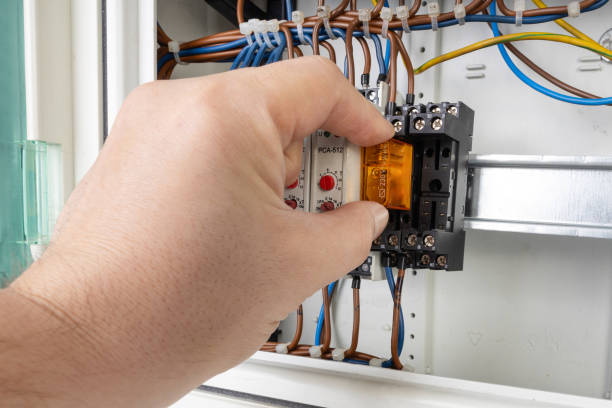 istock Close up of a hand inserting an electrical relay into a control panel with visible wiring and components. 2184527184
