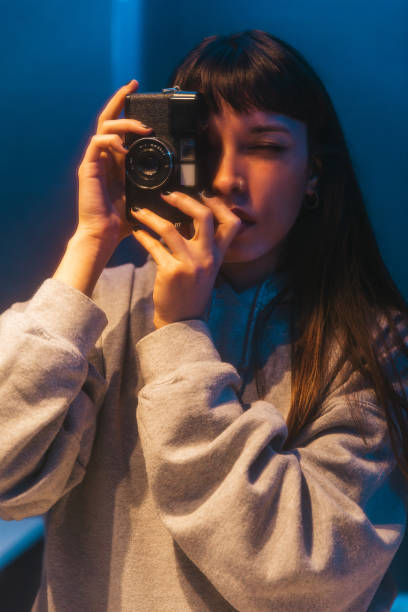 istock Young woman uses vintage point and shoot analog camera 2184527376