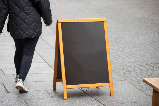 istock Person walking past an A-Frame sign on a pavement with copy space 2184528072