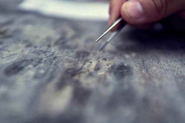 istock Close-up view of a hand using tweezers to manipulate a small object on a textured surface in a workshop environment 2184532992