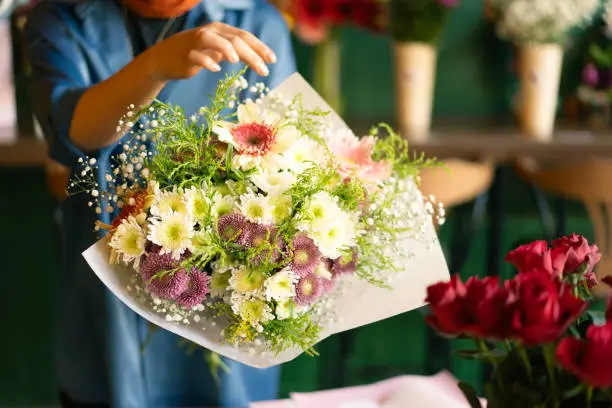 Woman's hand preparing bouquet in flower shop Woman's hand preparing bouquet in flower shop