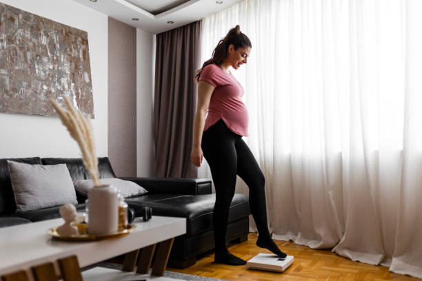 istock Pregnant woman weighing herself on a scale 2184538737