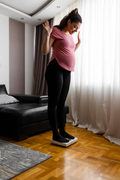 istock Pregnant woman weighing herself on a scale 2184539912