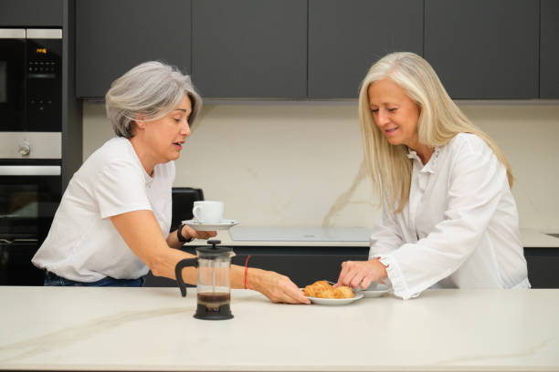 istock Senior women sharing breakfast and conversation in modern kitchen 2184542828