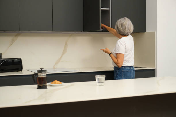 istock Senior woman putting away dishes in modern kitchen after breakfast 2184542875