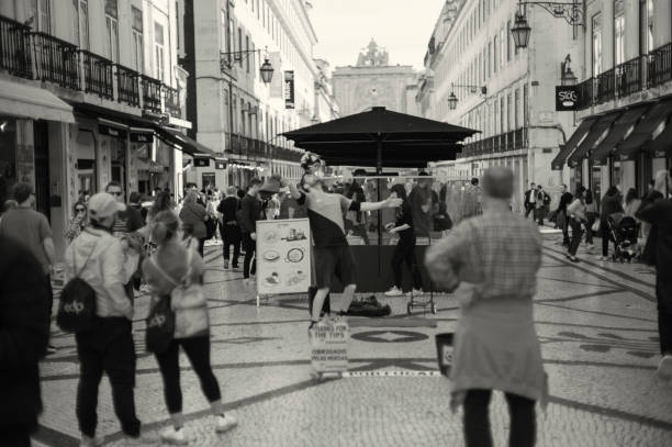Lisbon, Portugal - Mars 16, 2024: A street artist perfoms a juggling act wit a soccer ball at the Rua Augusta street in Lisbon downtown.