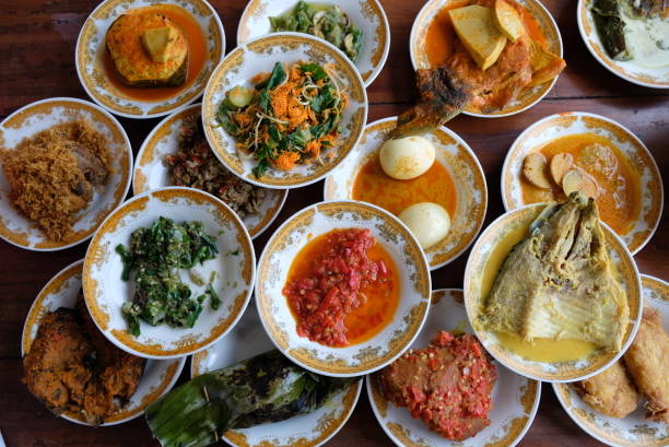 Assorted traditional Padang food is served in a plate on a table.