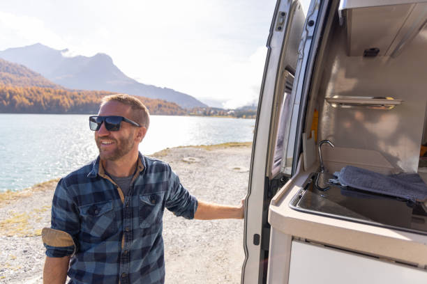 istock Happy Young Man Enjoying Lake View from Camper Van 2184554050