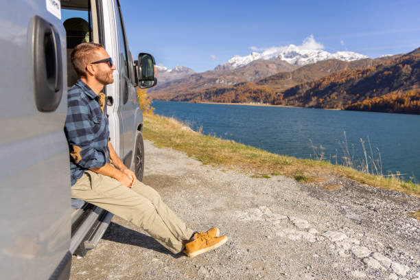 istock Young man contemplates lake view from his van 2184554252