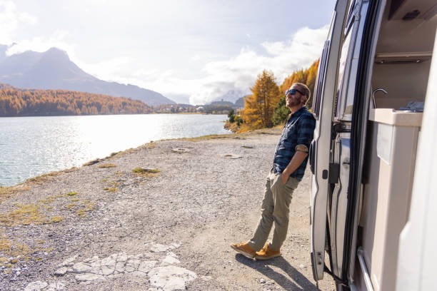 Man Enjoying Lakeside View by Camper Van on a Sunny Autumn Day