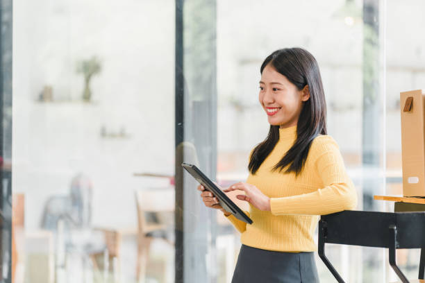 istock young woman in yellow sweater is smiling while using tablet in modern office setting. bright atmosphere enhances her cheerful demeanor, showcasing blend of technology and professionalism. 2184556725