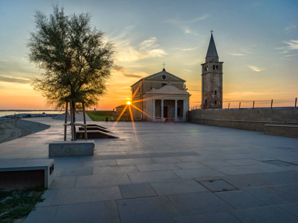 Landscape of the seafront in Caorle in Italy, with a small church illuminated at the first light of dawn