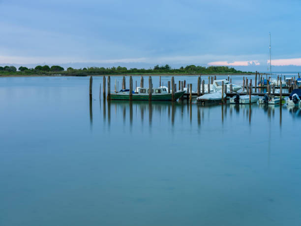 Landscape of the Caorle lagoon in Italy, with wooden pier, illuminated by the first warm lights of dawn