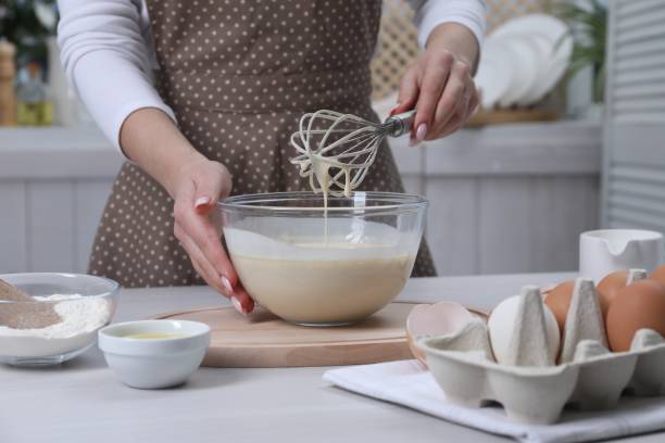 istock Woman making dough with whisk in bowl at table, closeup 2184565408