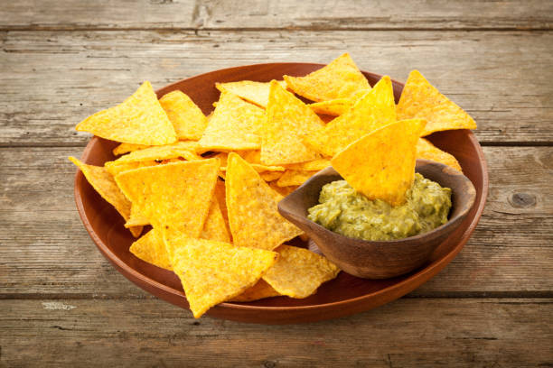 Wooden plate with Nachos and Guacamole on rustic table