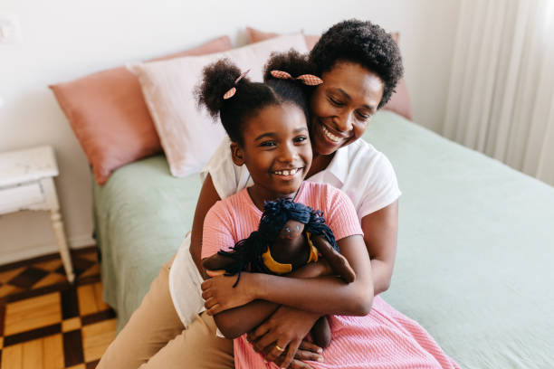 istock Mother hugging her daughter and her doll on the bed 2184574743