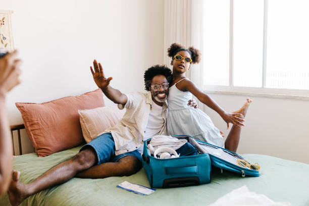 istock Excited father and daughter posing for mom's camera while packing for a vacation 2184575336