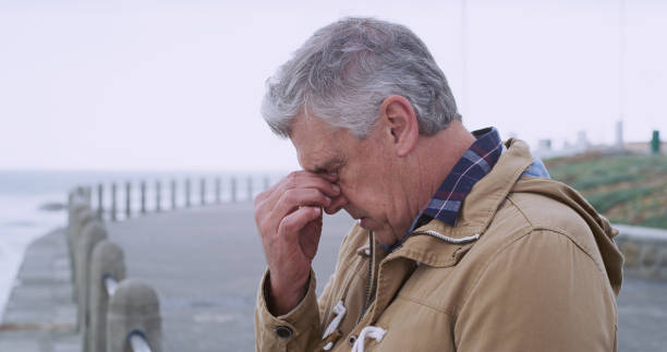 istock Senior man, thinking and depression by sea promenade with headache, stress and reflection. Person, sad and insight for mistake, crying and decision with anxiety by ocean, waves and outdoor 2184576208