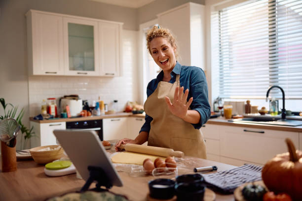 istock Happy woman having video call on touchpad while baking in the kitchen. 2184579099