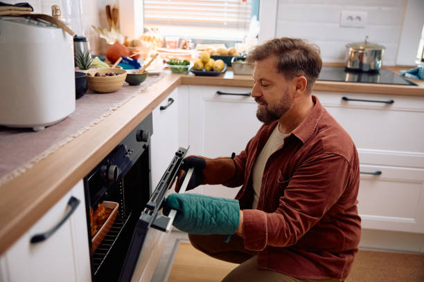 istock Smiling man preparing roast turkey in the kitchen. 2184579518