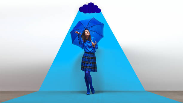 istock Woman in blue with umbrella standing under bright blue spotlight with cloud. Self-reflection, and emotional protection. Contemporary art collage. 2184580517