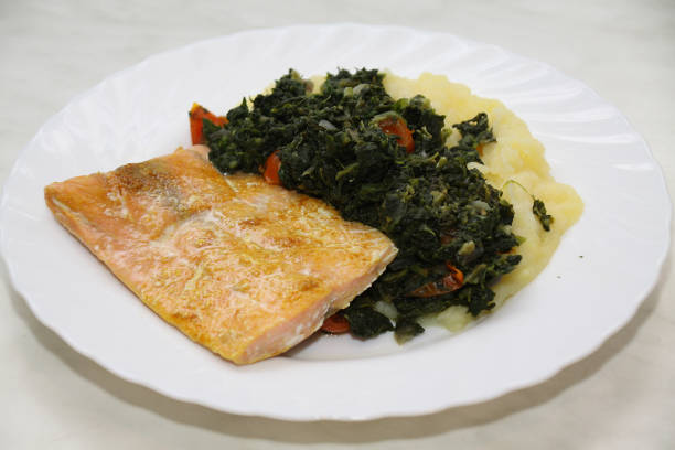 Close-up of a plate with salmon, spinach, tomatoes and mashed potatoes