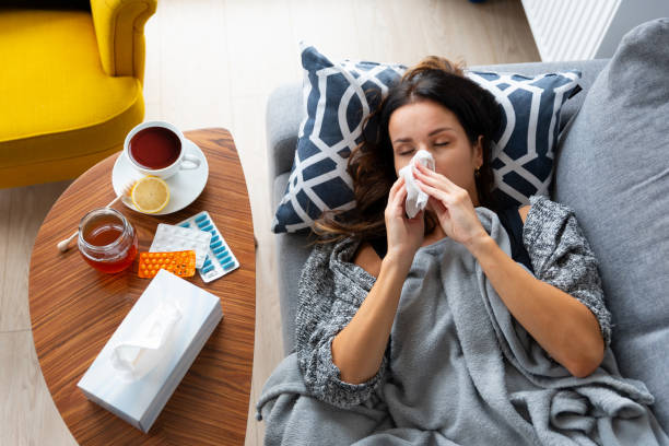 Woman is laying on a couch with a tissue