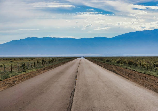 A long, straight road heading to great sand dunes national park in the summer