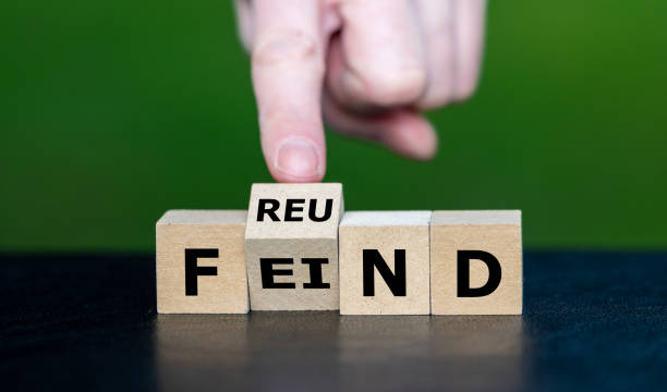 istock Hand turns cube and changes the German word 'Feind' (enemy) to 'Freund' (friend). 2184585895