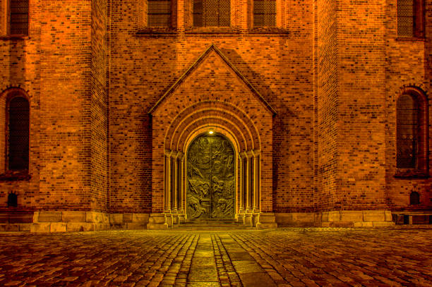 Gothic stone church entrance with pointed arch and heavy wooden doors. Historic medieval architecture detail, symmetrical facade, old European religious building exterior.