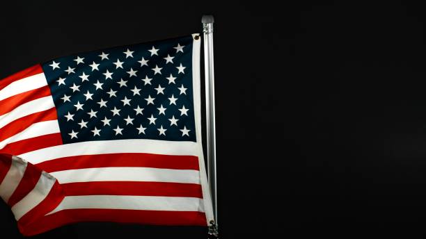 istock American Flag Waving Against Black Background. 2184599651