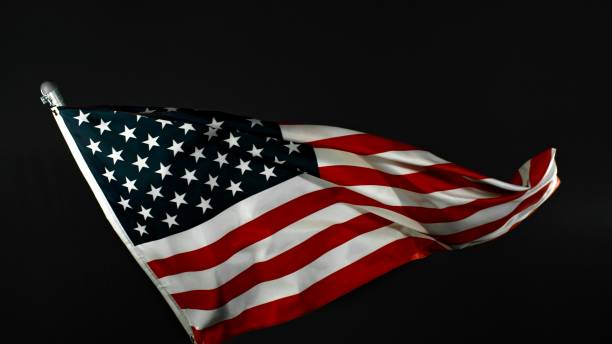 istock American Flag Waving Against Black Background. 2184599657