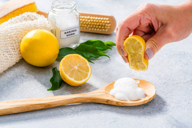 istock Natural and eco friendly home cleaning products: hand squeezing lemon on a spoon filled with baking soda 2184608865