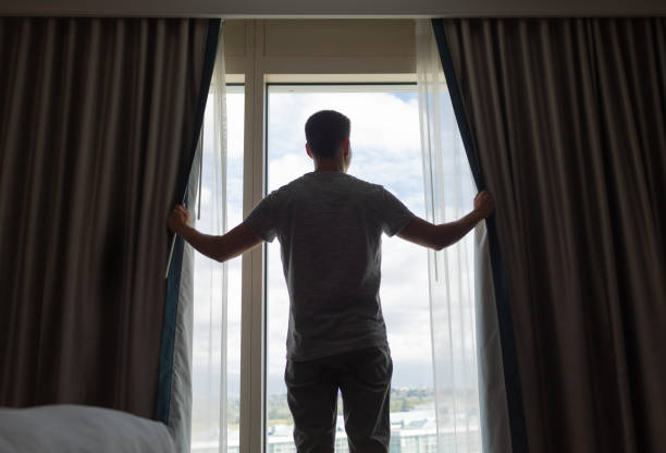 istock Men opening curtains and welcoming new day. 2184609177