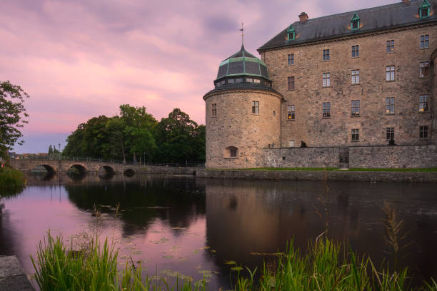 Orebro, Sweden- August 4, 2024: Stone Orebro Castle  at Svartan river against synset sky. Tourist atraction and history entusiast destination.  Copy space