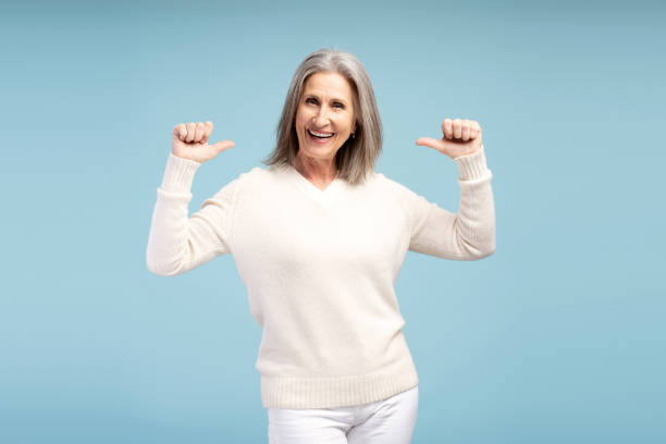 istock Smiling senior woman pointing fingers herself, posing isolated on blue background 2184609457