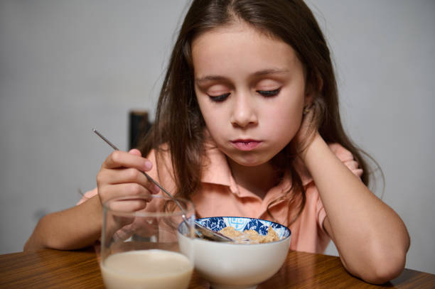 istock Young girl eating breakfast cereal with a pensive expression 2184616519