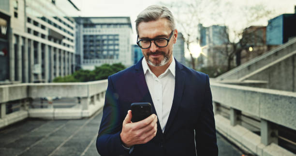 istock City, commute and phone with property developer outdoor for communication, networking or travel. App, corporate and direction with mature professional businessman in urban town to search for location 2184617236